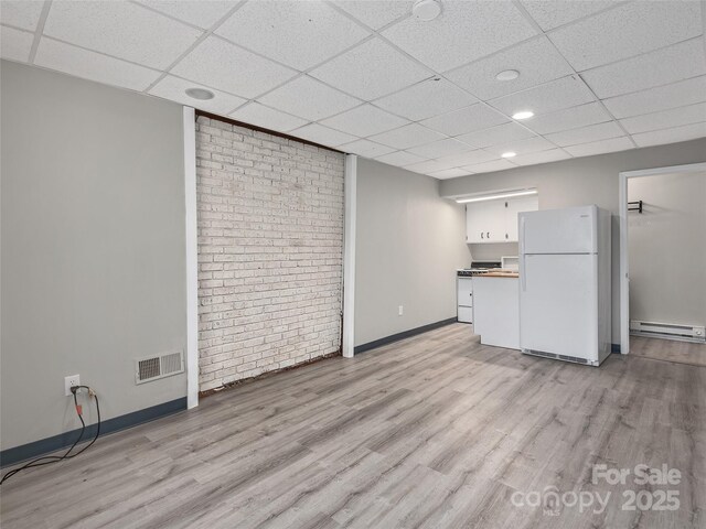 kitchen with light wood-style floors, freestanding refrigerator, visible vents, and baseboard heating