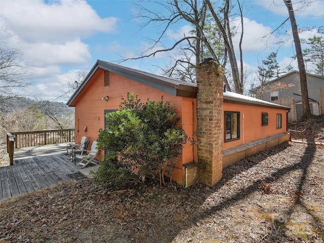 view of home's exterior featuring a chimney and a wooden deck