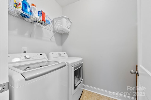 clothes washing area featuring light tile patterned floors, laundry area, independent washer and dryer, and baseboards