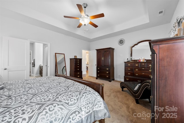 bedroom with ceiling fan, carpet flooring, visible vents, baseboards, and a raised ceiling