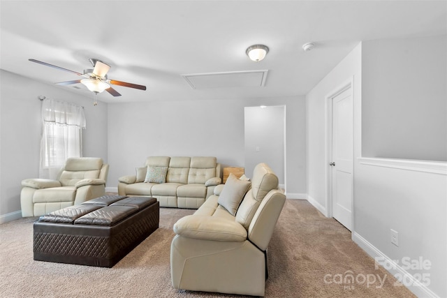 carpeted living room with attic access, baseboards, and ceiling fan