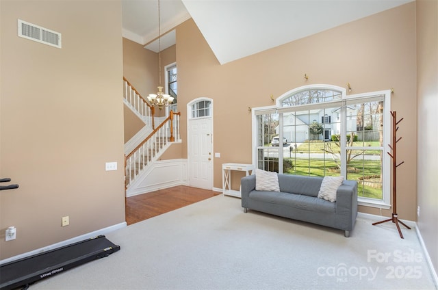 living area with visible vents, a notable chandelier, a high ceiling, and stairs