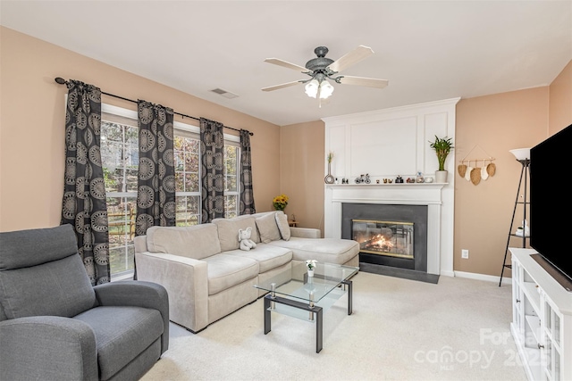 living area with visible vents, baseboards, ceiling fan, a fireplace with flush hearth, and light carpet