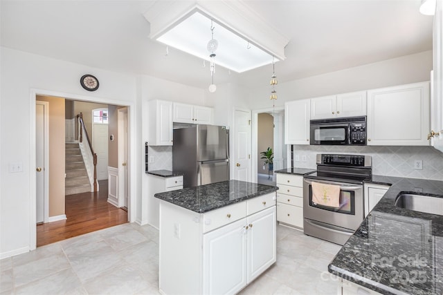 kitchen with dark stone counters, decorative backsplash, white cabinets, appliances with stainless steel finishes, and a center island