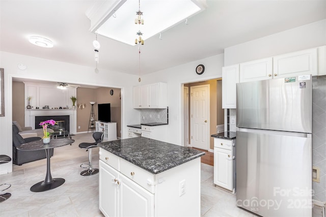 kitchen with white cabinets, a fireplace, a kitchen island, and freestanding refrigerator