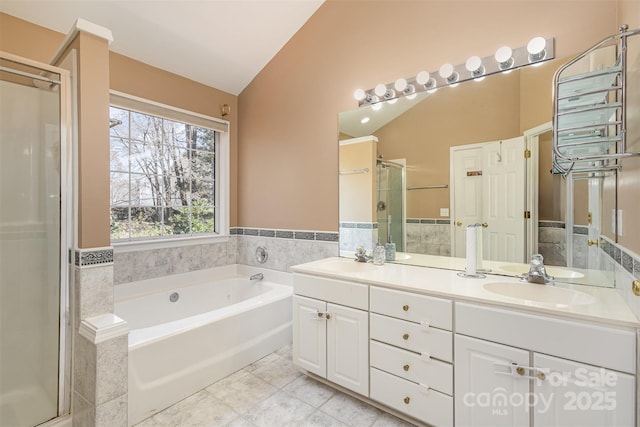 bathroom featuring lofted ceiling, a stall shower, a sink, a garden tub, and tile patterned floors