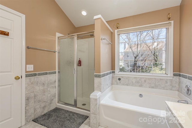 bathroom featuring tile patterned flooring, wainscoting, a stall shower, a bath, and tile walls