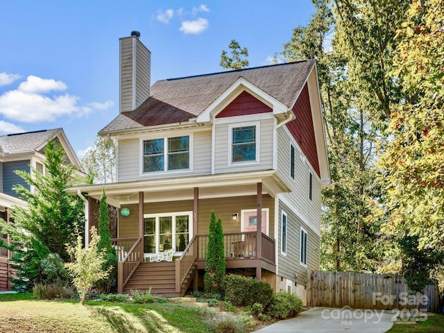 view of front of home with covered porch, fence, a chimney, and stairs