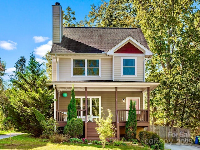 view of front of house with covered porch, roof with shingles, fence, and a chimney