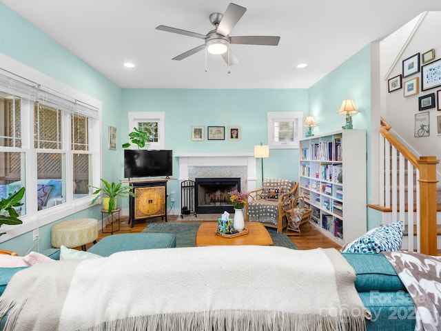 living area featuring a fireplace, a ceiling fan, wood finished floors, and recessed lighting