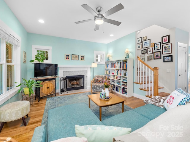 living room with stairway, a fireplace with raised hearth, wood finished floors, and recessed lighting