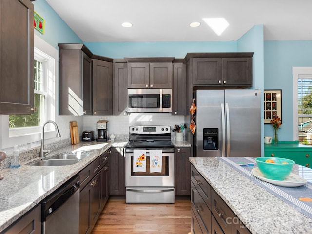 kitchen with appliances with stainless steel finishes, dark brown cabinets, and a sink