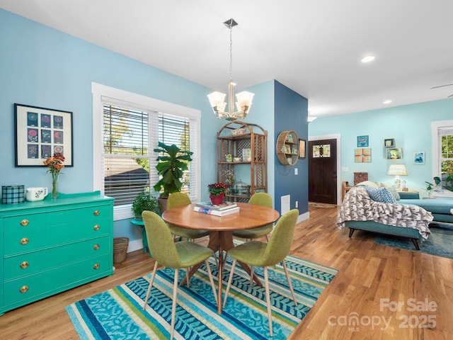 dining space with baseboards, light wood finished floors, recessed lighting, and an inviting chandelier