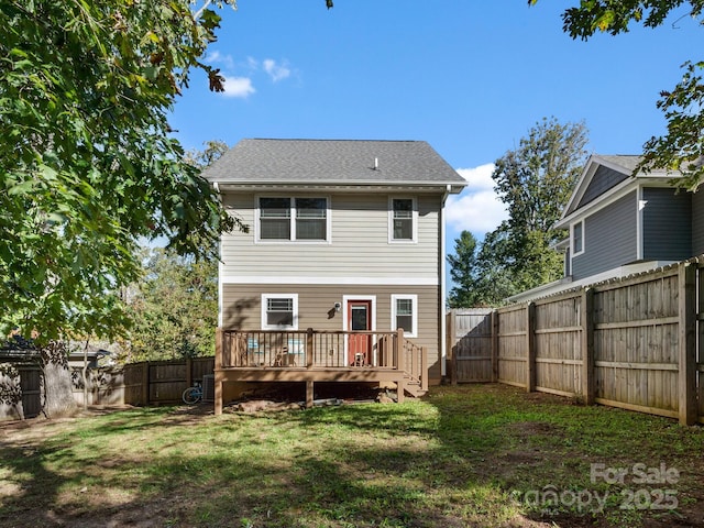 rear view of house featuring a fenced backyard, a lawn, and a wooden deck