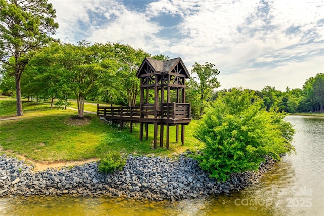 surrounding community with a deck with water view, a lawn, and a gazebo