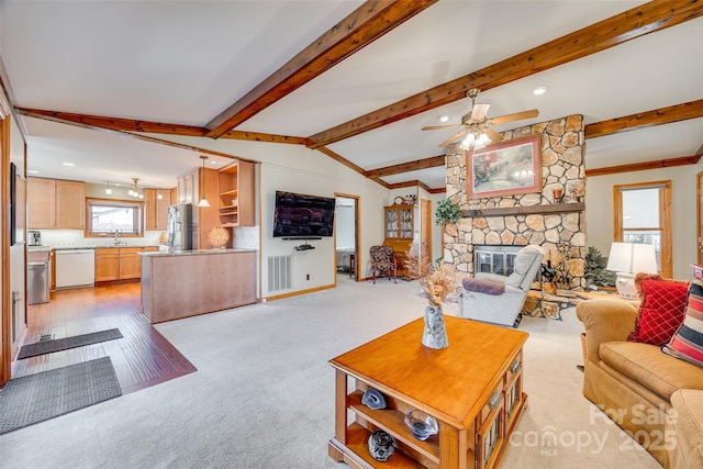 living area with a ceiling fan, visible vents, a stone fireplace, and lofted ceiling with beams