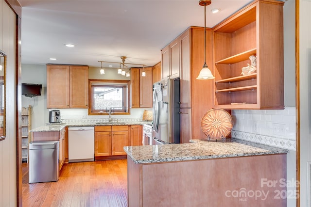 kitchen featuring white appliances, light stone counters, light wood finished floors, and a sink