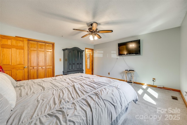 bedroom with a textured ceiling, carpet flooring, a ceiling fan, visible vents, and baseboards