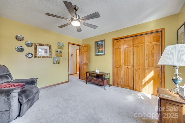 sitting room with a textured ceiling, baseboards, and light colored carpet