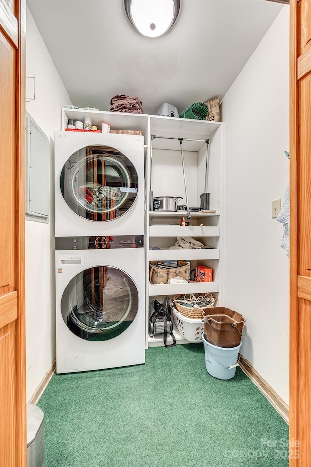 laundry room featuring laundry area, baseboards, stacked washer / drying machine, and carpet flooring