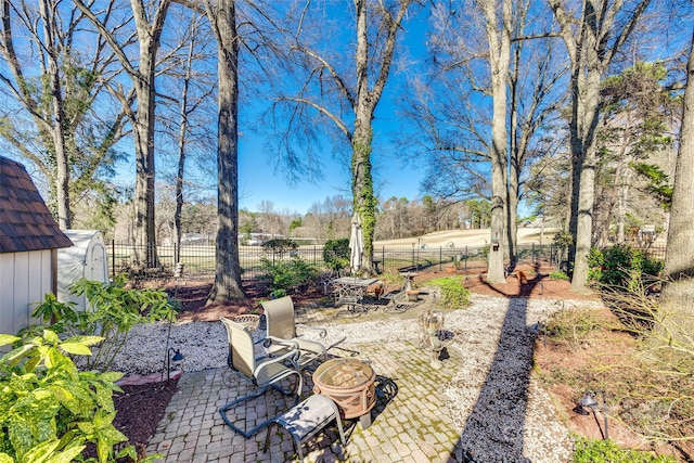 view of yard featuring an outbuilding, a patio area, fence, and a storage unit