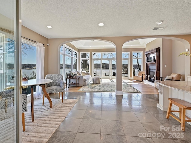 interior space with a textured ceiling, a fireplace, tile patterned flooring, and visible vents