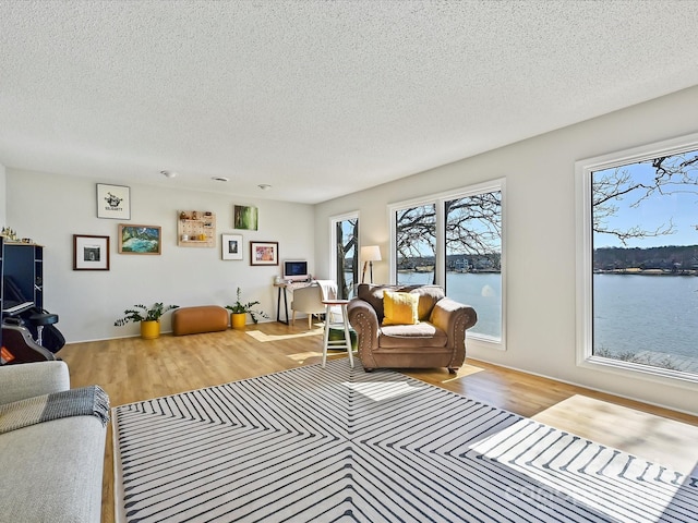 living room with a textured ceiling, a water view, and wood finished floors