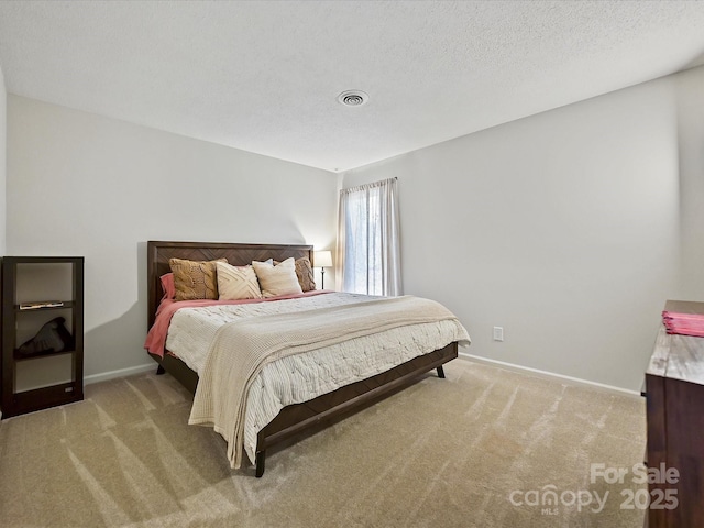 bedroom with light carpet, a textured ceiling, visible vents, and baseboards