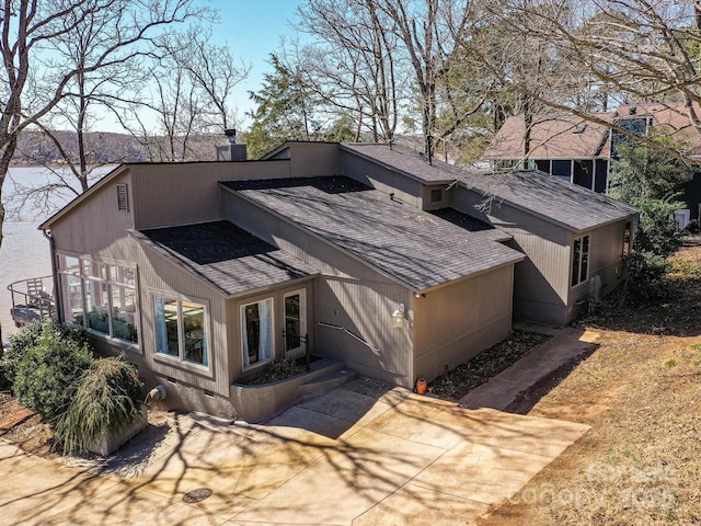 view of property exterior featuring a shingled roof and a chimney