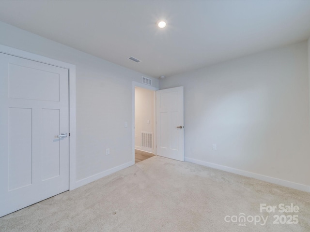 unfurnished bedroom with carpet, visible vents, and baseboards