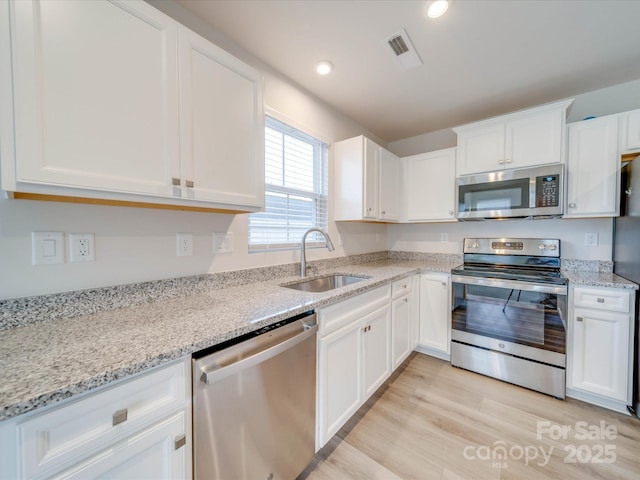 kitchen featuring stainless steel appliances, light wood-style floors, white cabinetry, a sink, and recessed lighting