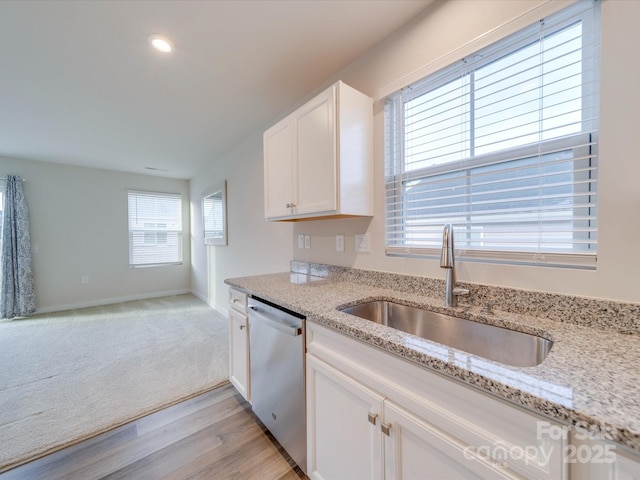 kitchen featuring white cabinets, light colored carpet, a sink, light stone countertops, and stainless steel dishwasher