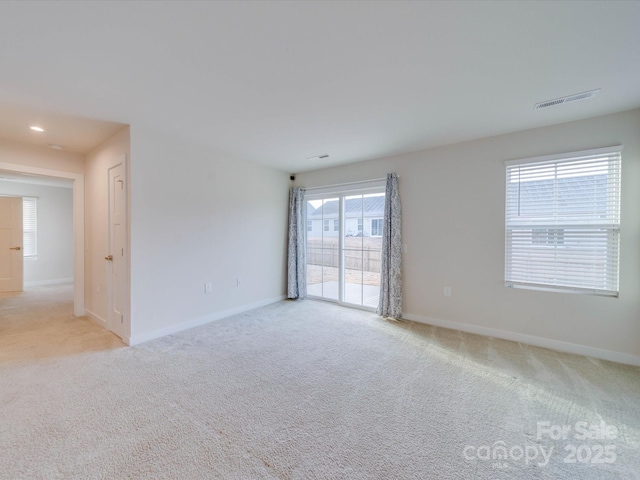 spare room with visible vents, light carpet, and baseboards