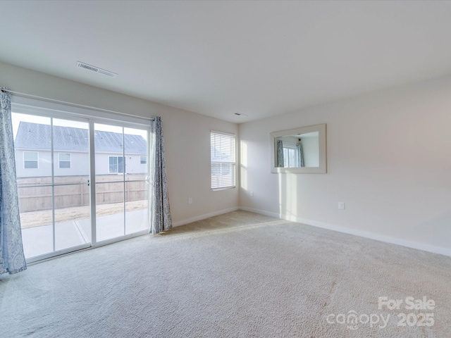 unfurnished room featuring baseboards, visible vents, and light colored carpet