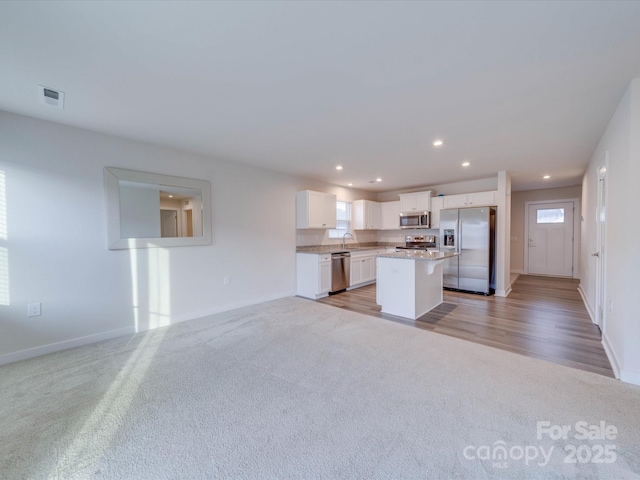 kitchen featuring white cabinets, a kitchen island, open floor plan, stainless steel appliances, and recessed lighting