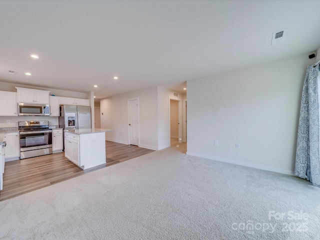 kitchen featuring stainless steel appliances, a center island, light colored carpet, and recessed lighting