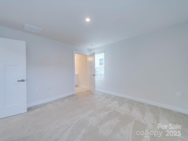 empty room featuring light colored carpet, visible vents, and baseboards