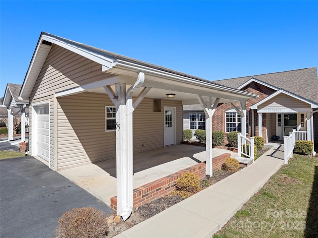 view of front of home with an attached garage, covered porch, and driveway