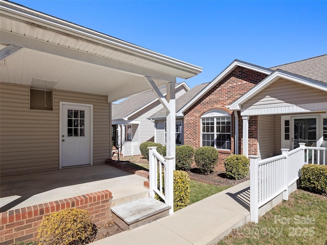 entrance to property with a porch and brick siding