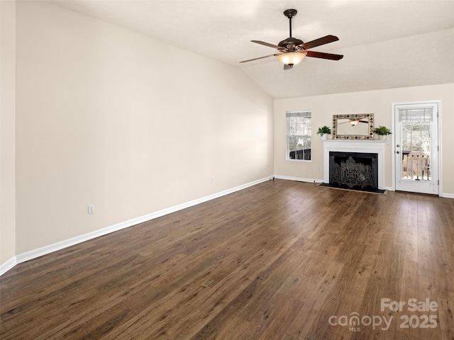 unfurnished living room featuring a fireplace with raised hearth, lofted ceiling, a ceiling fan, baseboards, and dark wood-style floors