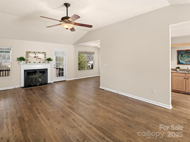 unfurnished living room with a fireplace, lofted ceiling, ceiling fan, a sink, and wood finished floors