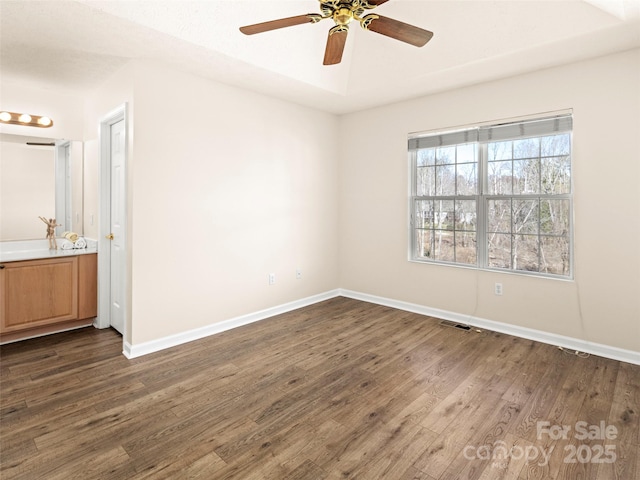 spare room featuring dark wood-style floors, ceiling fan, visible vents, and baseboards