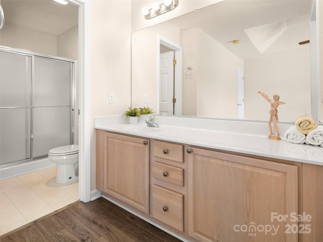 bathroom with wood finished floors, a stall shower, vanity, and toilet