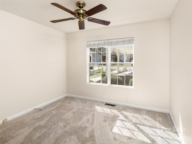 carpeted empty room featuring ceiling fan, visible vents, and baseboards