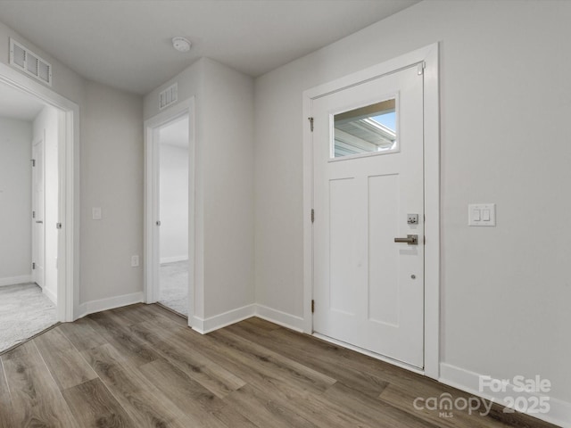 foyer with baseboards, visible vents, and wood finished floors