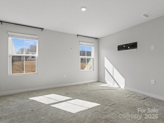 carpeted empty room with plenty of natural light, visible vents, and baseboards