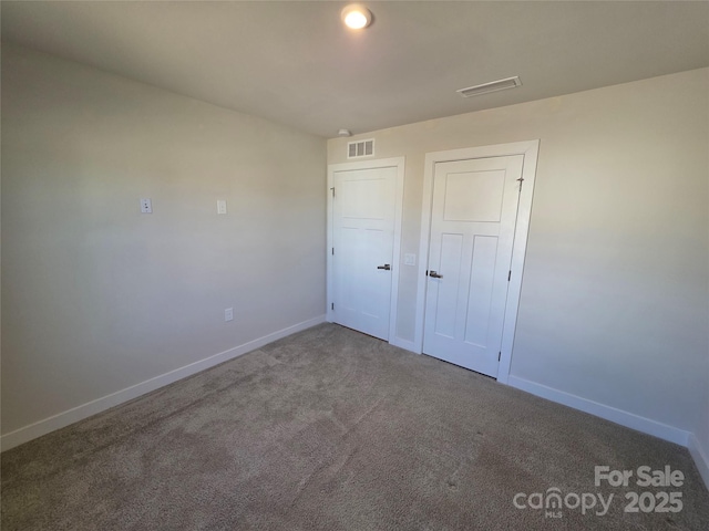 unfurnished bedroom with carpet floors, visible vents, and baseboards