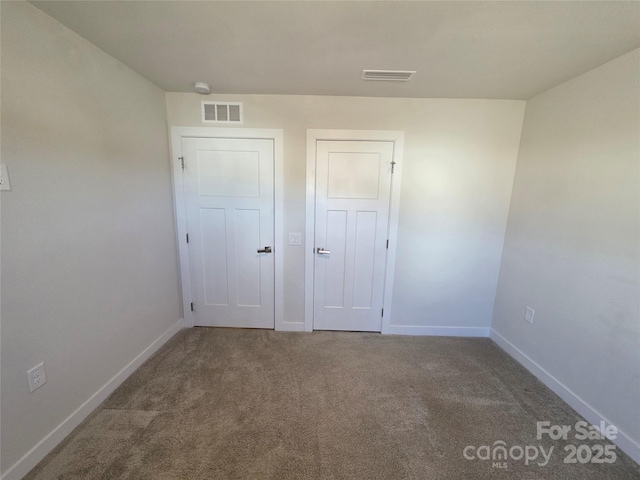 unfurnished bedroom featuring carpet floors, visible vents, and baseboards