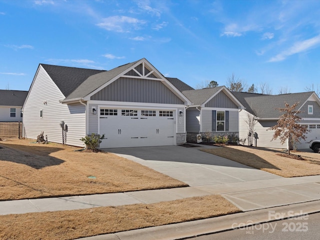 view of front of home with board and batten siding, roof with shingles, driveway, and an attached garage