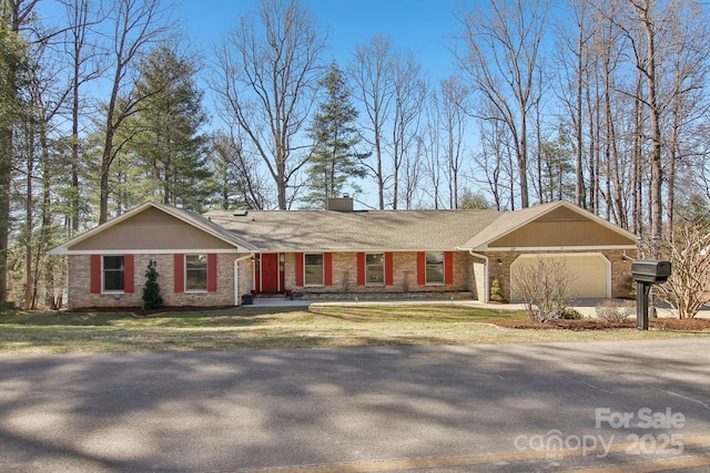 single story home featuring concrete driveway, a chimney, an attached garage, a front lawn, and brick siding